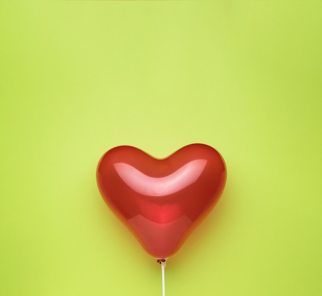 A big red inflatable heart on a green background. Space for text.