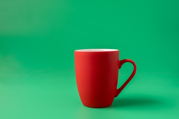 Big red mug on green background, minimal concept.