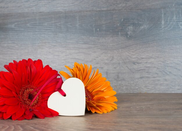 Big red and orange flowers with heart shape on rustic wooden table