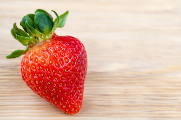 Big red ripe strawberry on wooden table