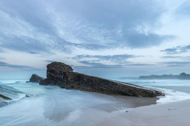 The big rock on the beach playing with the waves