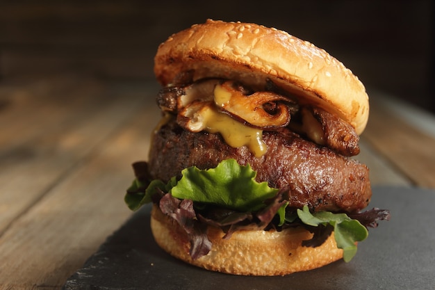 big rustic hamburger with mushrooms on a wooden table