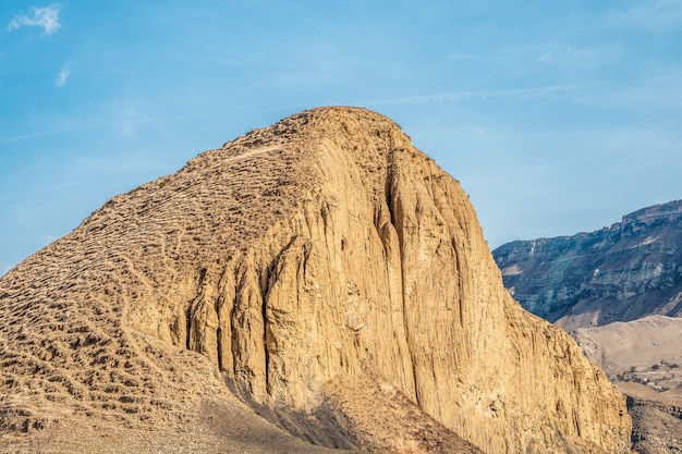 大きな砂の山。美しい砂漠の風景、砂と石の間に青い空を背景に大きな山があります。