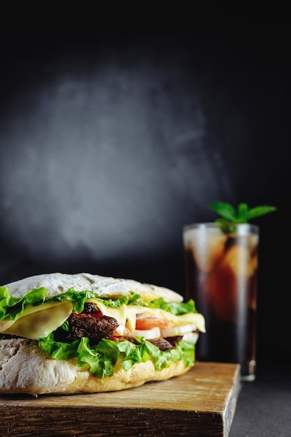 Big sandwich on black background rosemary cucumber wooden board