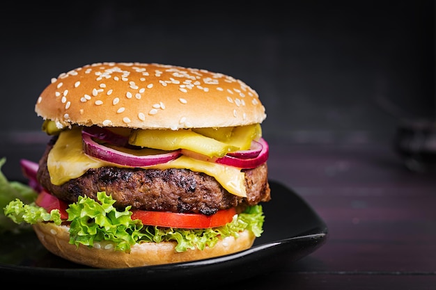 Big sandwich hamburger burger with beef tomato cheese pickled cucumber and red onion