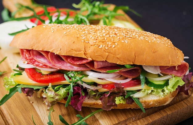 Big sandwich with ham, salami, tomato, cucumber and herbs