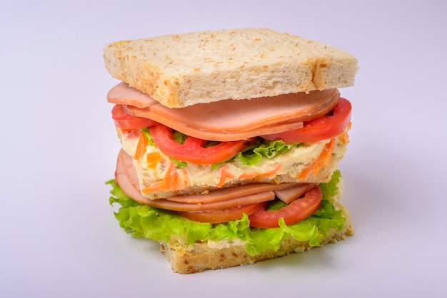 Big sandwich with smoked ham cream lettuce and tomato isolated on white background Fast food