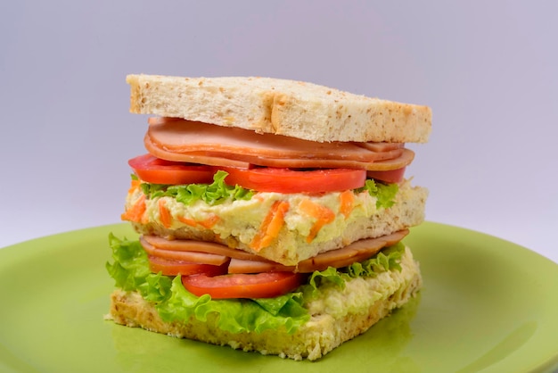 Big sandwich with smoked ham with lettuce and tomato on green plate Fast food