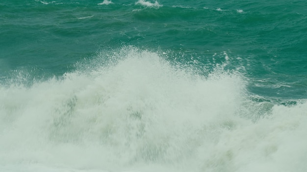 大きな海の波が砂浜に飛び散り春の嵐の間美しい強い大きな波と泡が浮かびます