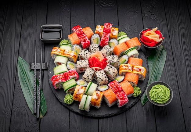Большой набор азиатских блюд Суши и роллы на темном фоне