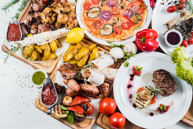 Big set of different dishes with meat vegetables pizza and spices flatlay on white background