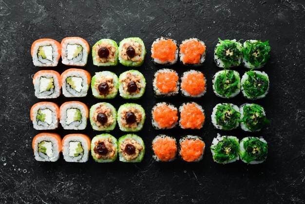 Big set of pieces of sushi rolls on black stone background Top view Free space for your text