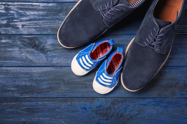 Photo big and small shoes on wooden background father's day composition