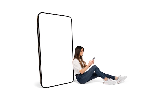 Big smartphone caucasian girl sitting floor with phone on her hand and leaning bis smartphone