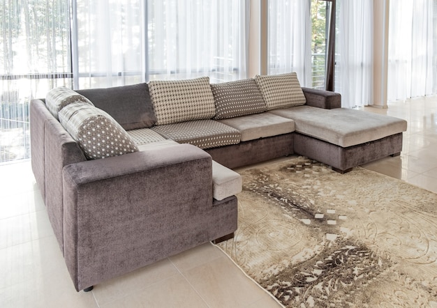 Big sofa and a large windows interior decor with morning sunlight from the windows