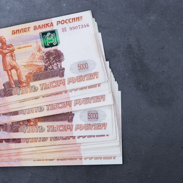 Big stack of Russian money banknotes of five thousand rubles lying on grey cement.