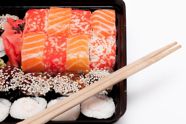 Grande set di sushi ib scatola di plastica nera su sfondo bianco, vista dall'alto vicino, copia dello spazio.