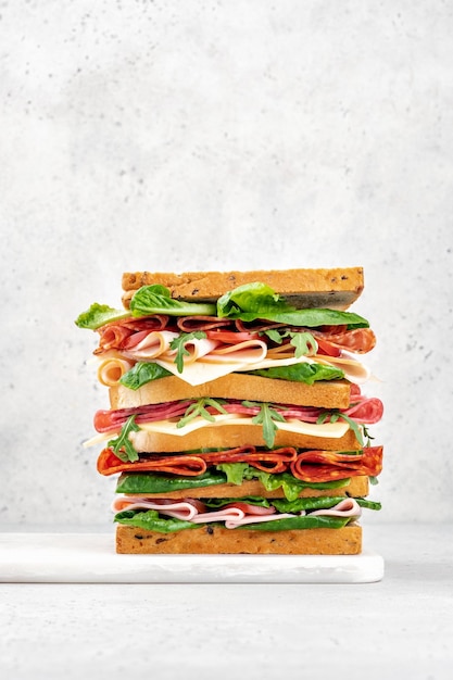 Photo big tasty sandwich with ham salami salad cheese and tomatoes on white background