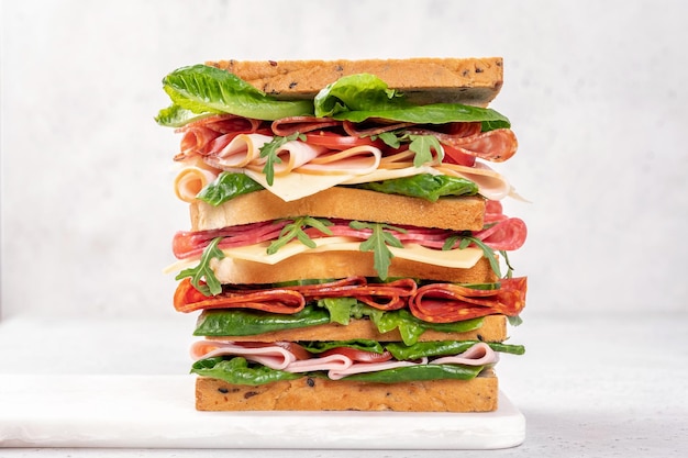 Big tasty sandwich with ham salami salad cheese and tomatoes