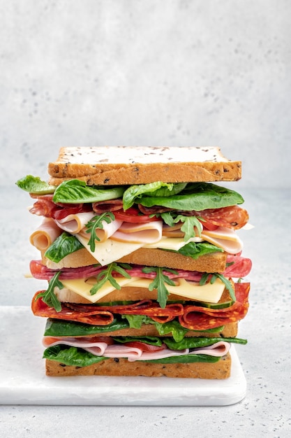 Big tasty sandwich with ham salami salad cheese and tomatoes