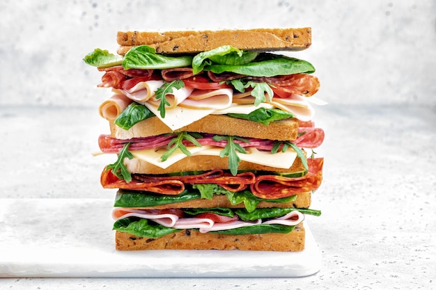 Big tasty sandwich with ham salami salad cheese and tomatoes