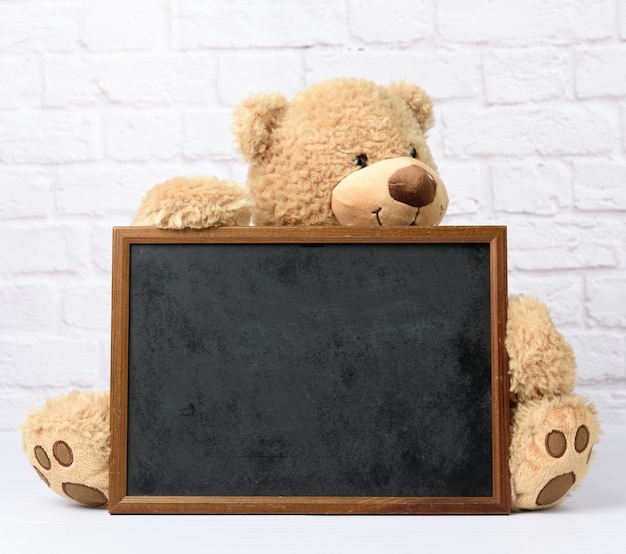 Big teddy bear holding empty rectangular wooden frame