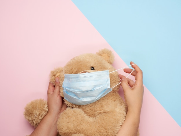 Big teddy bear in medical masks on blue pink