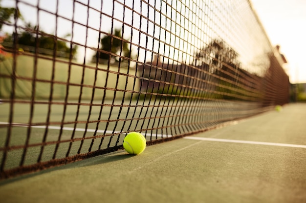 Большой теннисный мяч у сетки, никто, открытый корт. Активный здоровый образ жизни, спортивная игра с концепцией ракетки