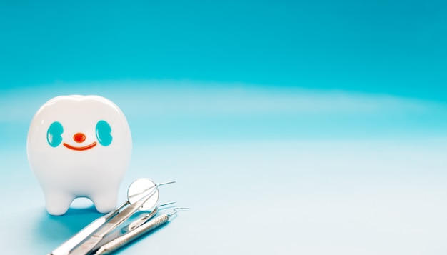 Photo big tooth and dentist tool on blue background.