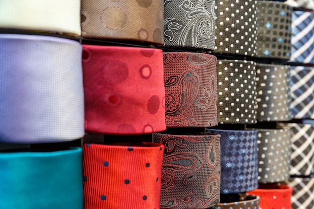 Большое разнообразие галстуков разных цветов на полке в магазине мужской одежды