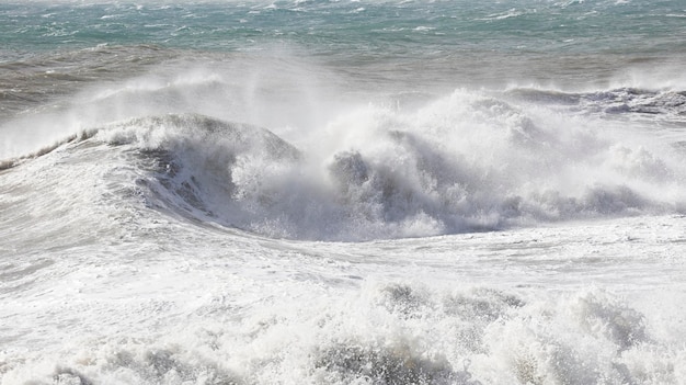 Big waves breaking on the shore with white forma