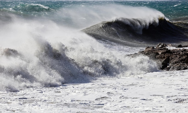 Big waves breaking on the shore with white forma