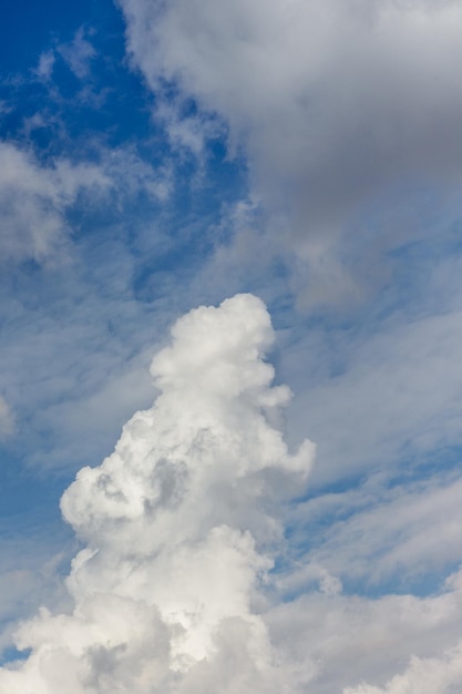 Большое белое вьющееся облако в голубом небе, вертикальный формат_