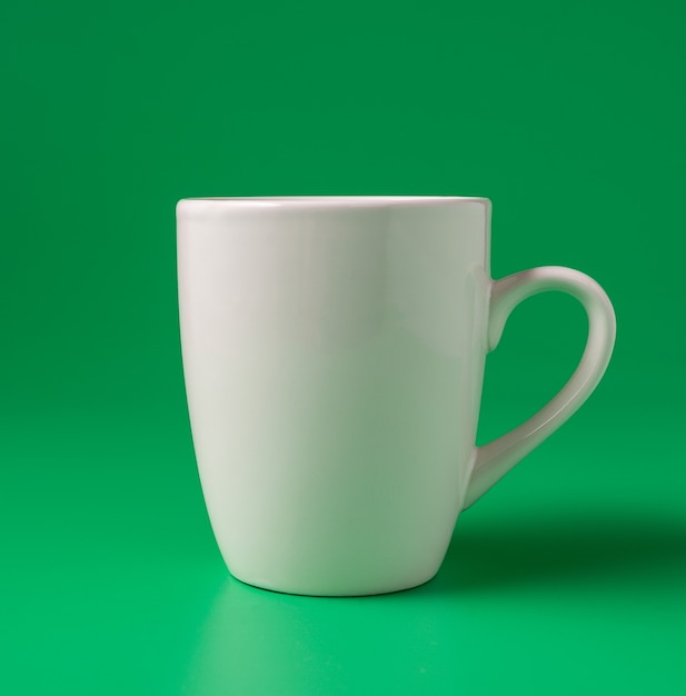 緑の背景に大きな白いマグカップ、最小限のコンセプト。