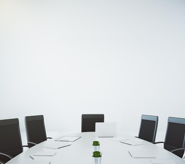 Big white oval table with laptop and chairs at white wall background