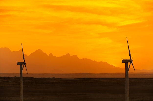 Big wind turbines in the desert against mountains