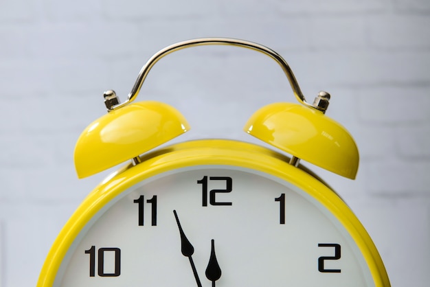 Big yellow alarm clock with arrows close up.