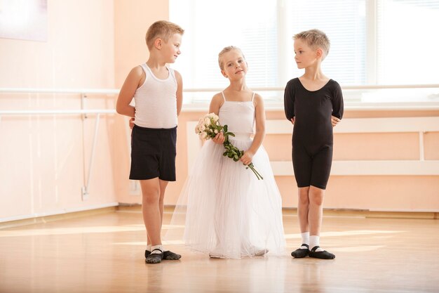 Bij balletdansles: jonge jongens en een meisje met bloemen die gracieus poseren