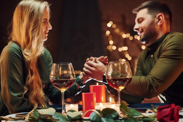 Bij de handen vasthouden Jonge mooie paar hebben samen romantisch diner binnenshuis