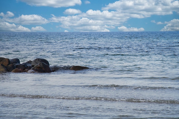 Bij de zee van de Oostzee Stone groynes reiken in het blauwe water Witte wolken in de lucht.