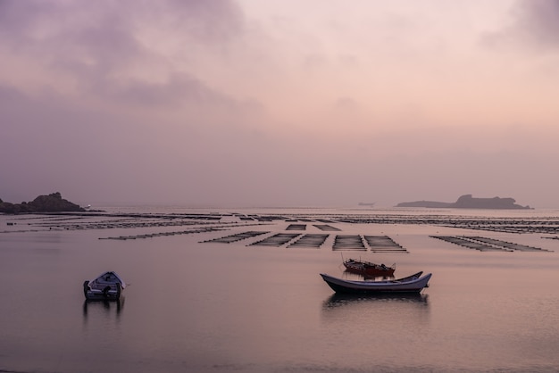 Bij de zeewierboerderij voor zonsopgang in de ochtend zijn er zeewierrijen en boten