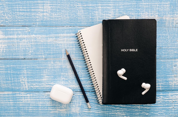 Bijbel notitieboekje en koptelefoon op een blauwe houten achtergrond plat leggen kopie ruimte