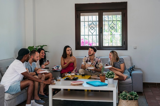 Bijeenkomst van vrienden die een hapje eten in de woonkamer van een huis