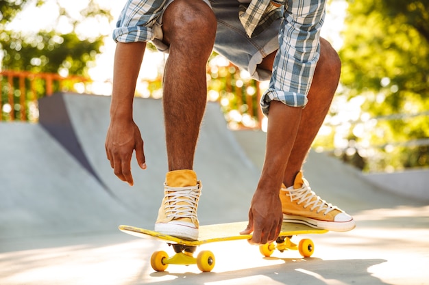 Bijgesneden afbeelding van een Afrikaanse man met skateboard rijden