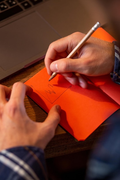 Bijgesneden afbeelding van een casual zakenman of freelancer die zijn werk plant op een notebook die op een laptop werkt...