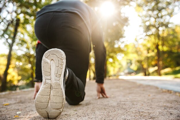 Bijgesneden afbeelding van knappe jonge sport fitness man loper buiten in park.