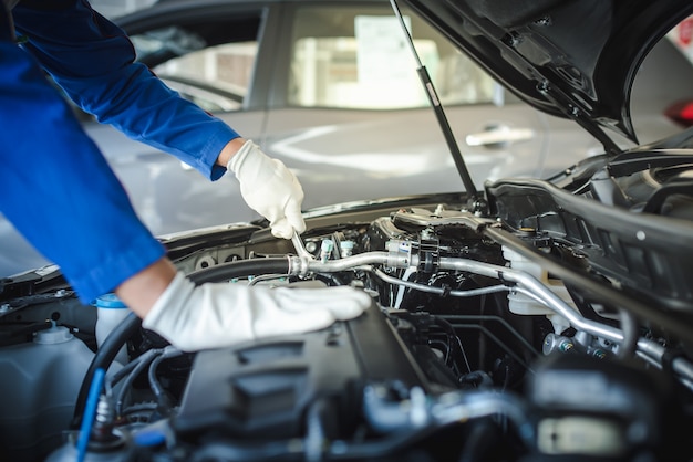 Bijgesneden afbeelding van knappe monteur in uniform werkt in auto service. Autoreparatie en -onderhoud.