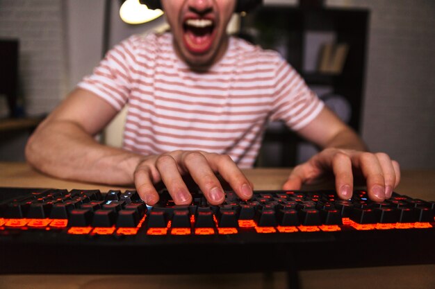 Foto bijgesneden afbeelding van schreeuwende gamer spelen van videogames op computer