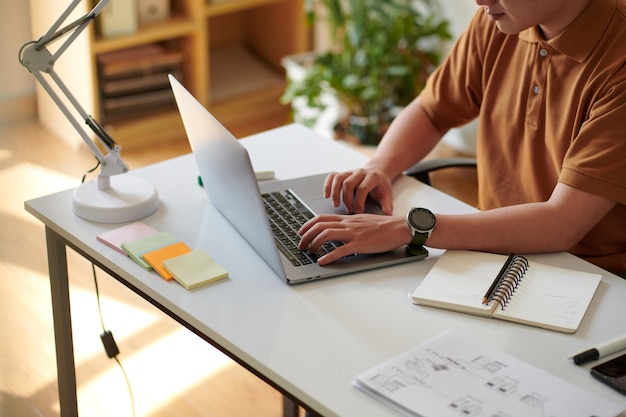 Bijgesneden afbeelding van softwareontwikkelaar die aan een project werkt aan het bureau in het thuiskantoor