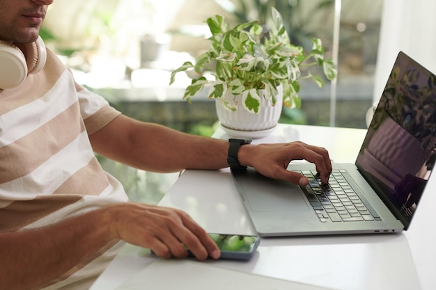 Foto bijgesneden afbeelding van softwareontwikkelaar die op laptop in thuiskantoor werkt